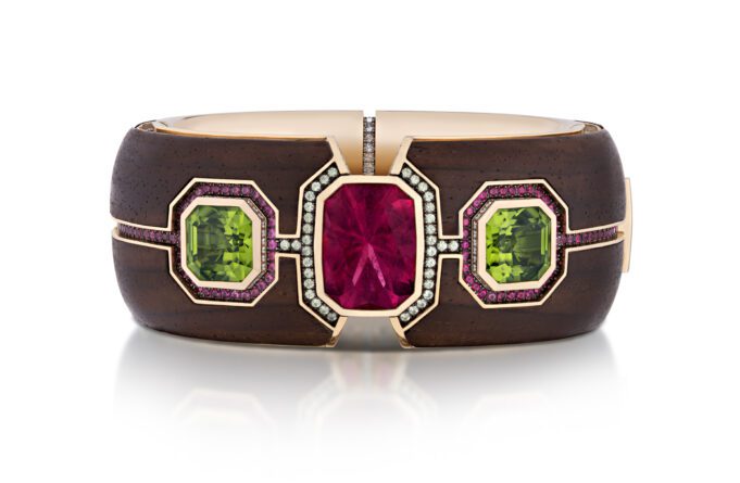 Elegant bracelet with red and green gemstones set in brown material.