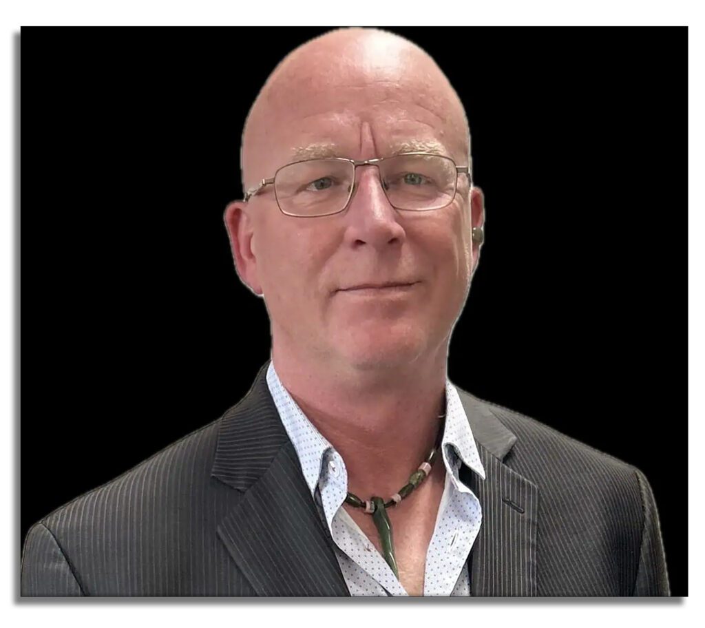Portrait of a man with glasses and short black hair against a plain background.